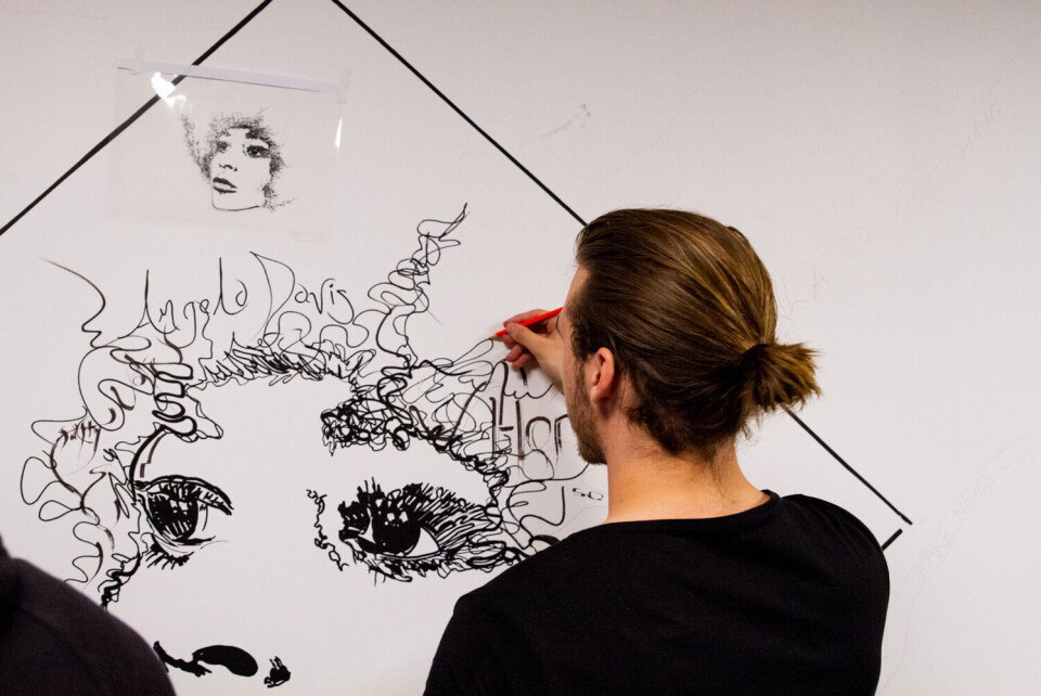 DISKUSJON. Leder av studentbaren, Peter Rolfsen, finner fram sin indre kunstner og får hjelpe Nimi med å tegne håret til menneskerettighetsforkjemperen som nå pryder Diskuterbar sin vegg. FOTO: ANNA JAKOBSEN