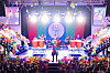 Sceneshow med en artist i sentrum, ballonger, publikum og sterke scenelys.